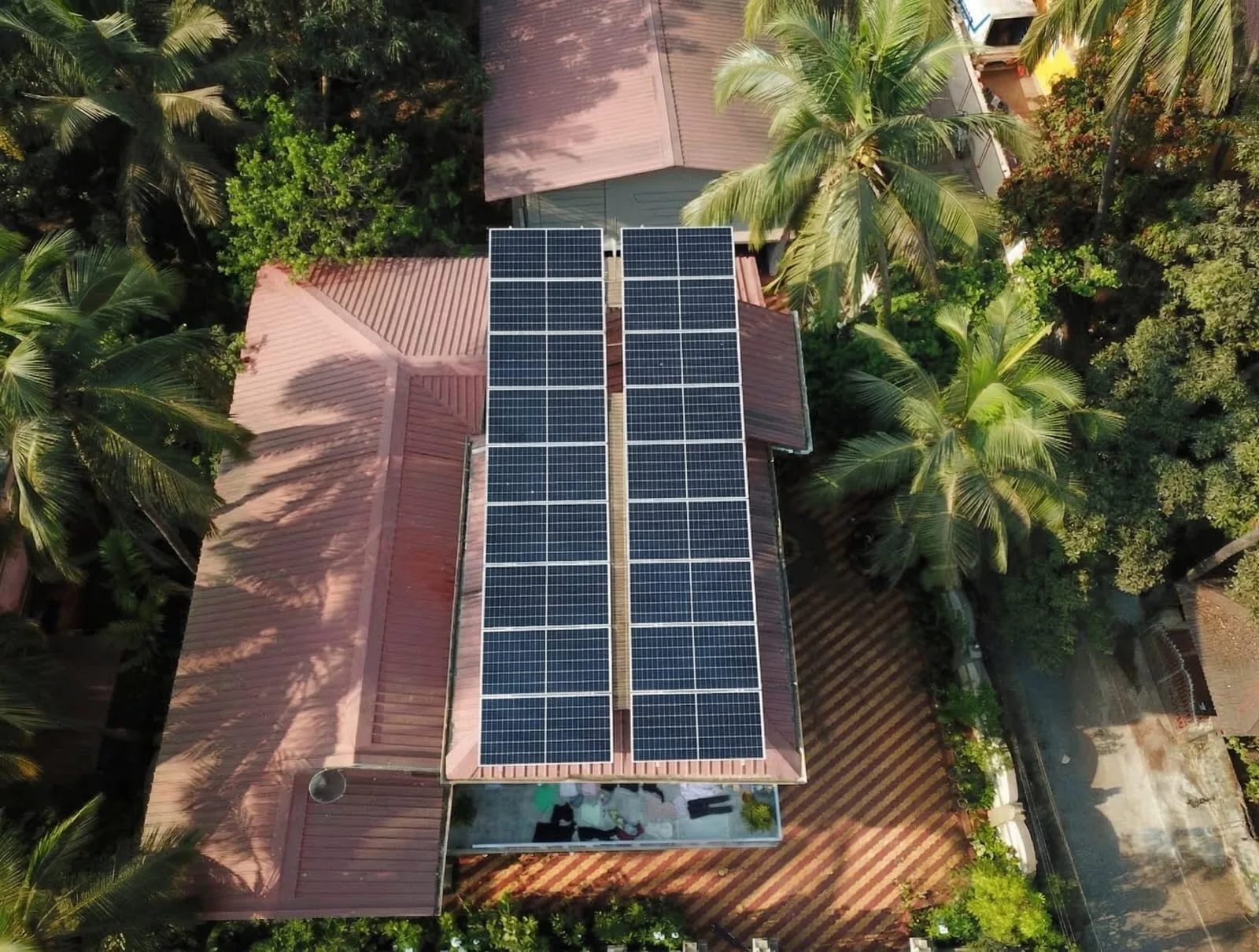 Narrow solar array on a red roof among trees